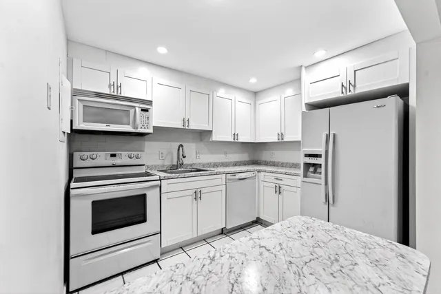 a kitchen with stainless steel appliances granite countertop a stove a sink and a refrigerator