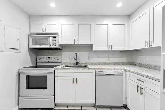 a kitchen with white cabinets and appliances