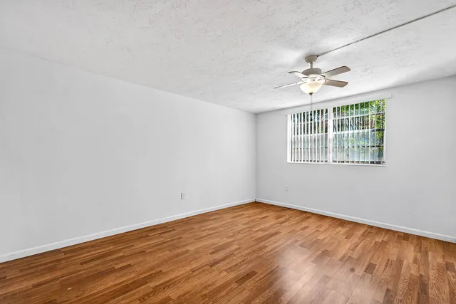 a view of empty room with wooden floor and fan