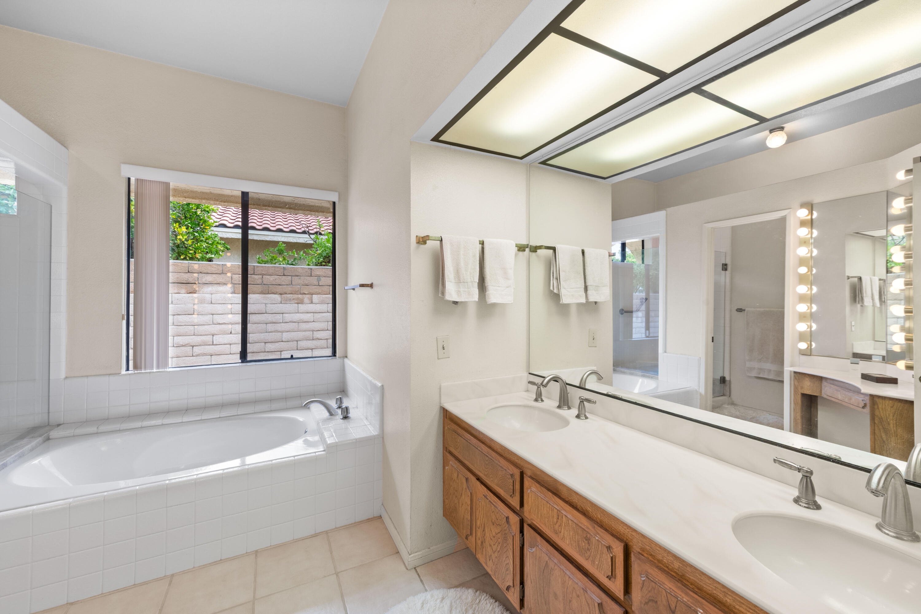 53 San Simeon Place Rancho Mirage, CA 92270 - Photo 16 of 30 a bathroom with a double vanity sink bathtub and next to a window