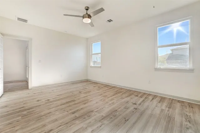an empty room with wooden floor and ceiling fan