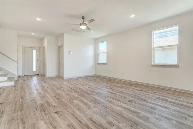 a view of an empty room with wooden floor and a window