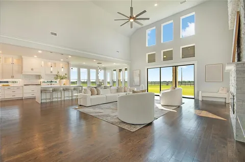 a living room with couches a coffee table and kitchen view with wooden floor