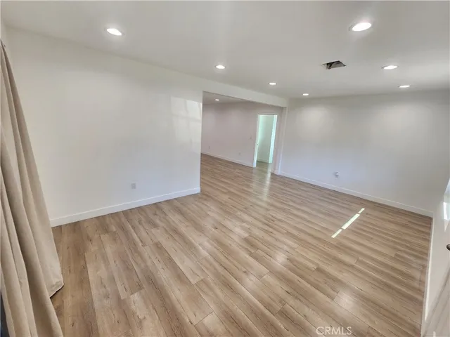 an empty room with wooden floor and natural light