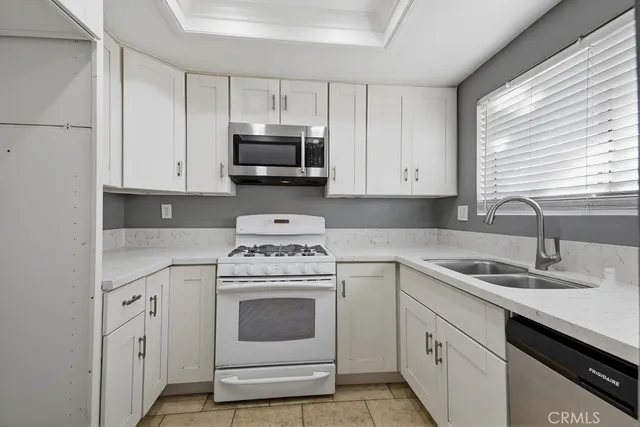 a kitchen with white cabinets appliances and sink