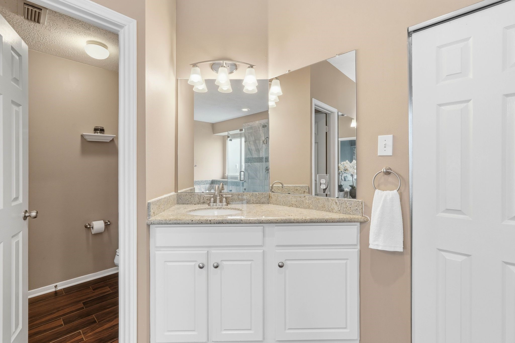 2515 Woodsboro Drive Spring, TX 77388 - Photo 21 of 44 This photo showcases a bright bathroom with a granite countertop, white cabinetry, and a large mirror. A sliding door leads to the walk in closet.