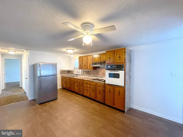 a kitchen with stainless steel appliances a refrigerator a sink dishwasher a oven with white cabinets and wooden floor