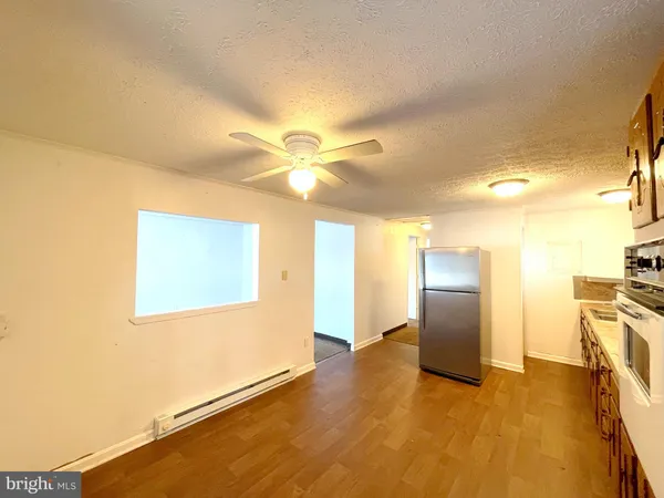 a view of an empty room with wooden floor and a ceiling fan
