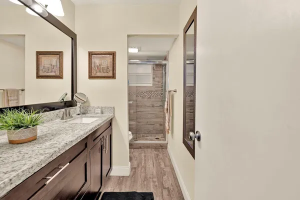a bathroom with a granite countertop sink a mirror and shower
