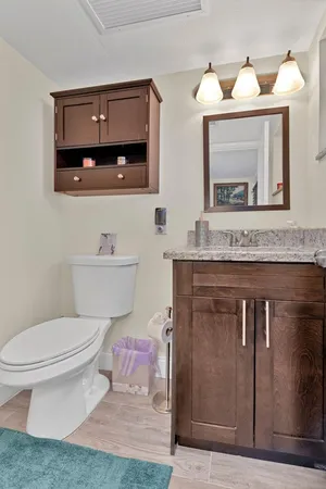 a bathroom with a granite countertop toilet sink and mirror