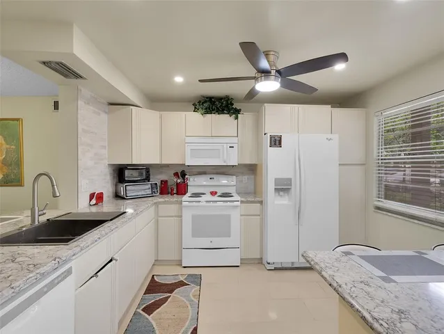 a kitchen with stainless steel appliances granite countertop a refrigerator sink and white cabinets