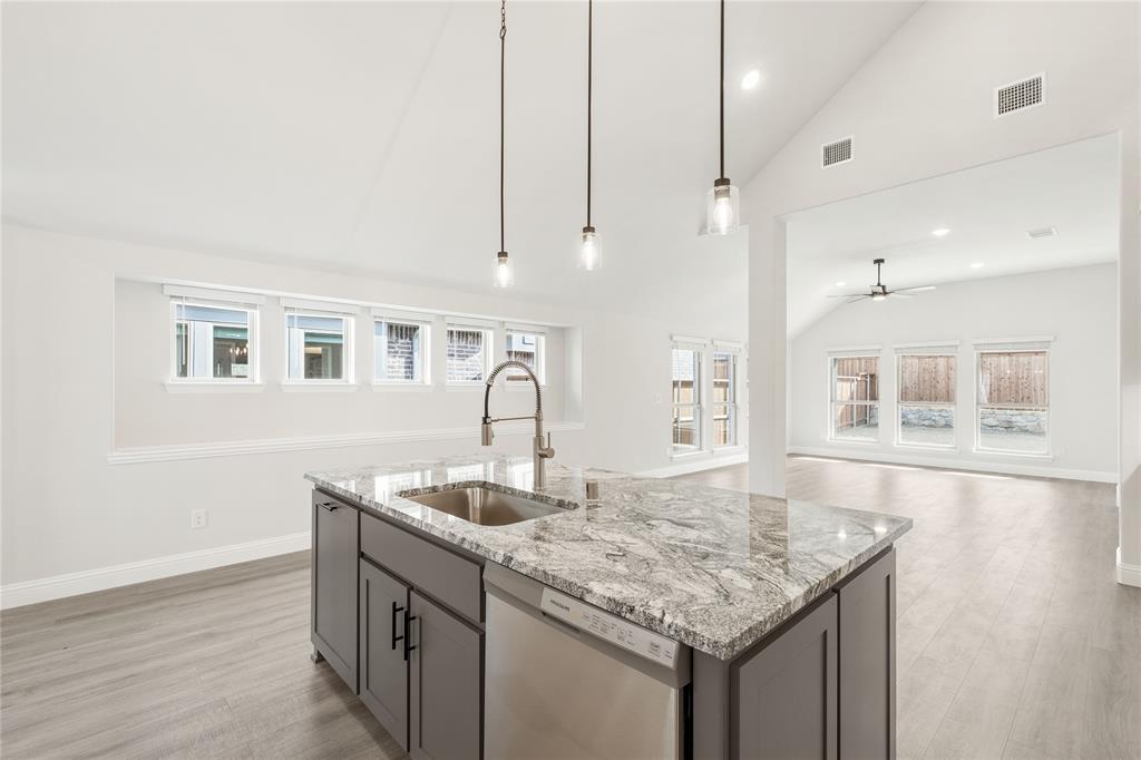 14505 Lovelace Street Pilot Point, TX 76258 - Photo 11 of 37 a kitchen with granite countertop a sink a center island and stainless steel appliances