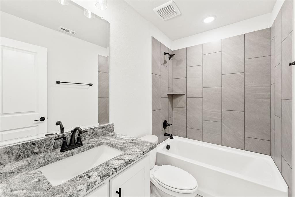 14505 Lovelace Street Pilot Point, TX 76258 - Photo 16 of 37 a bathroom with a granite countertop bathtub shower sink vanity mirror and toilet