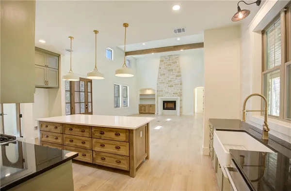 a kitchen with stainless steel appliances kitchen island granite countertop a sink a stove and a wooden floors