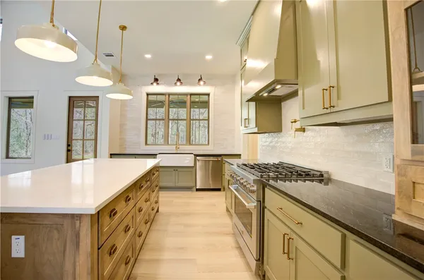 a kitchen with stainless steel appliances granite countertop a sink a stove and a wooden floors