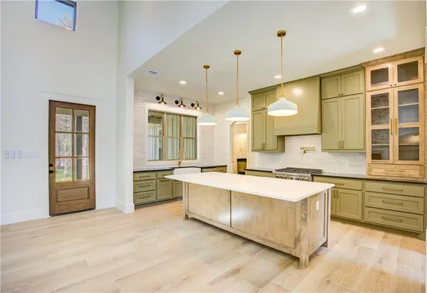 a large kitchen with a large counter top a sink stainless steel appliances and cabinets