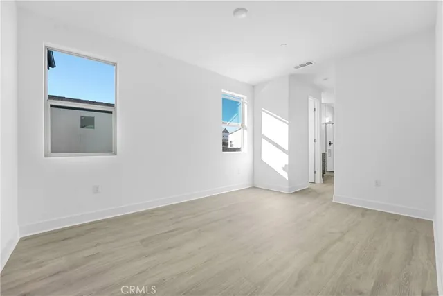 a view of an empty room with window and wooden floor