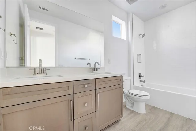 a bathroom with a double vanity sink a toilet and a bathtub