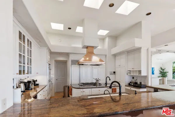 a kitchen with stainless steel appliances a stove a sink and white cabinets