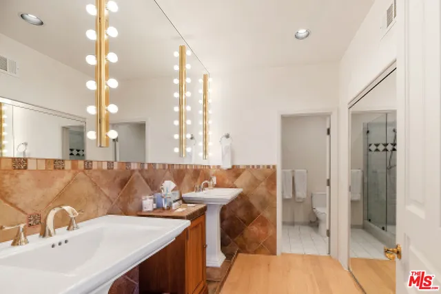 a bathroom with a double vanity sink a toilet a mirror and shower