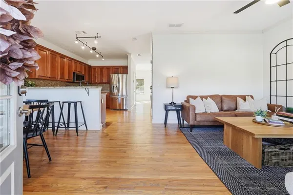 a living room with stainless steel appliances furniture and a wooden floor