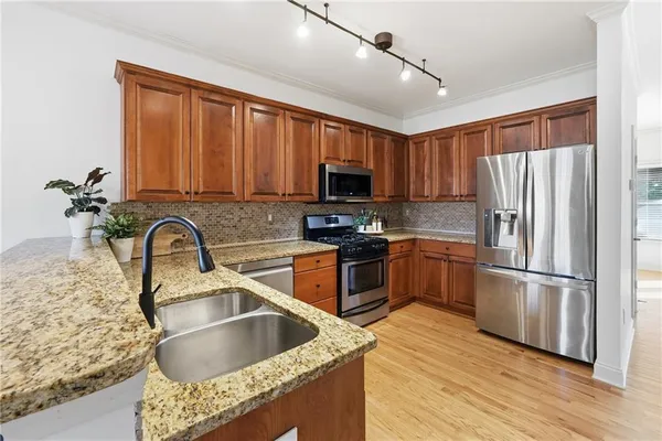 a kitchen with stainless steel appliances granite countertop a refrigerator sink and wooden cabinets