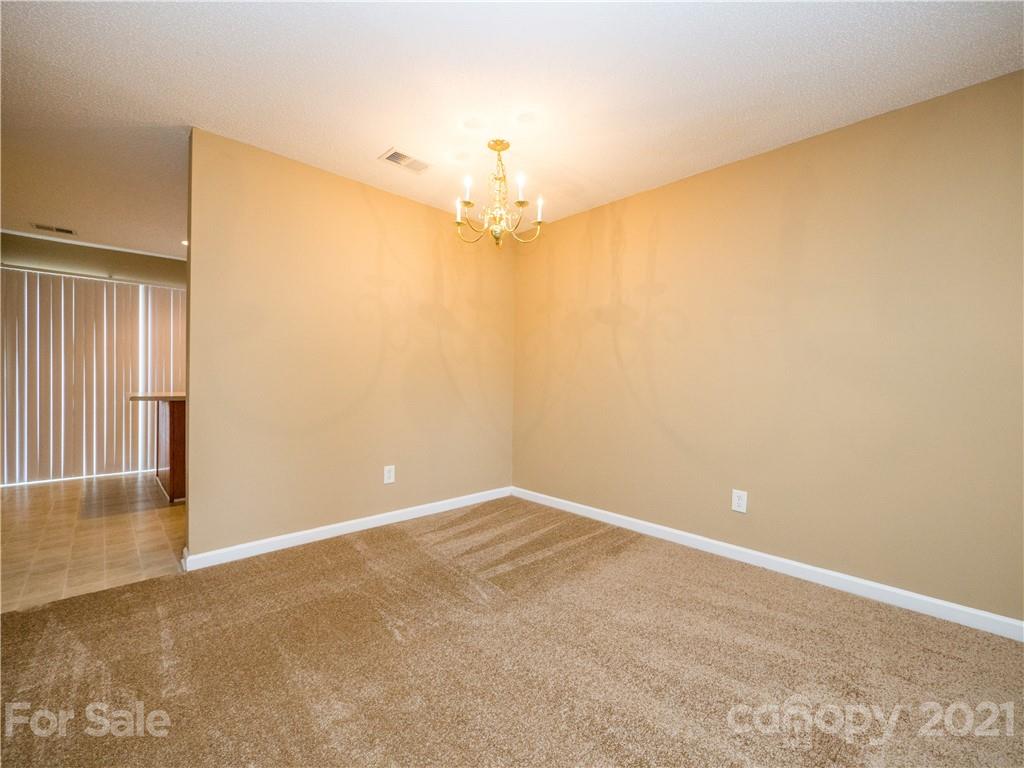 8178 Rudolph Road Charlotte, NC 28216 - Photo 8 of 20 an empty room with a chandelier fan and windows