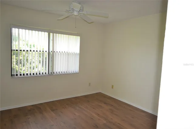 an empty room with wooden floor fan and windows