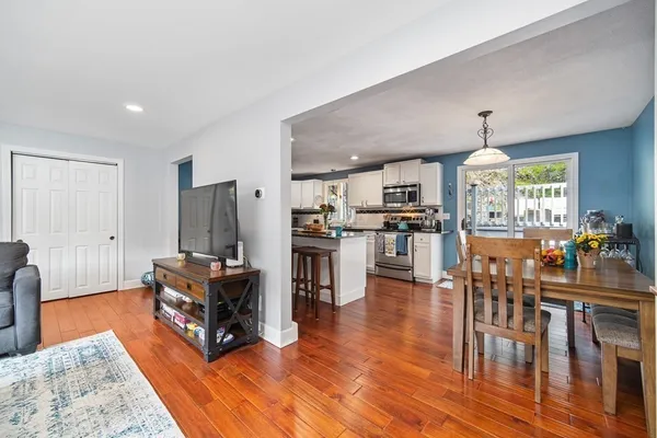 a living room with stainless steel appliances granite countertop furniture wooden floor and a kitchen view