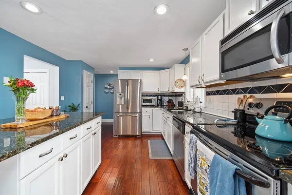 a kitchen with stainless steel appliances kitchen island granite countertop a stove a sink and a microwave