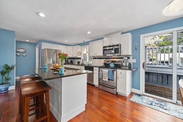 a kitchen with granite countertop a stove top oven a sink dishwasher a dining table and chairs with wooden floor