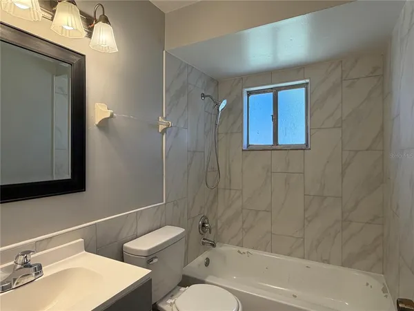 a bathroom with a bathtub shower sink vanity and toilet
