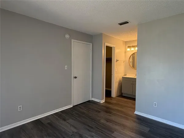 a view of an empty room with wooden floor and closet