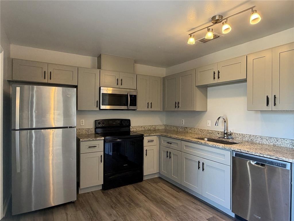 1215 Ravida Circle Orlando, FL 32825 - Photo 5 of 22 a kitchen with a sink a refrigerator a microwave and cabinets