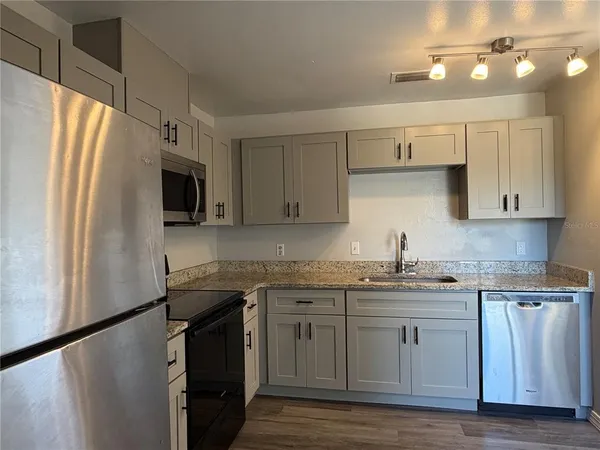 a kitchen with stainless steel appliances granite countertop a sink a stove a refrigerator and cabinets