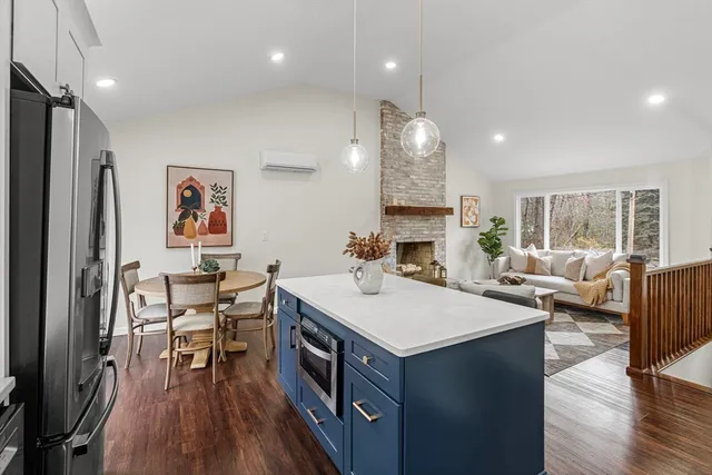 a living room with stainless steel appliances furniture a rug and a kitchen view