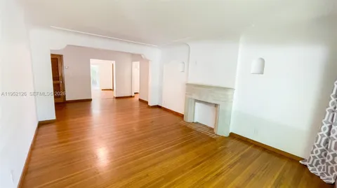a view of empty room with wooden floor and fireplace