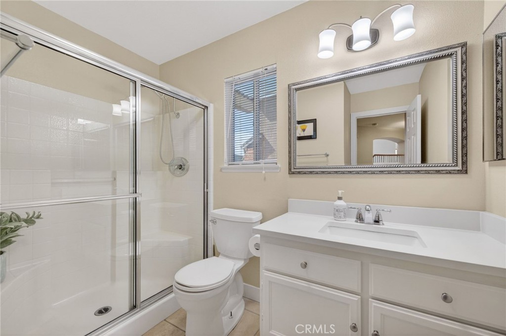 28322 Corte Ocaso Temecula, CA 92592 - Photo 39 of 75 a bathroom with a toilet a sink a glass door a shower a mirror and vanity