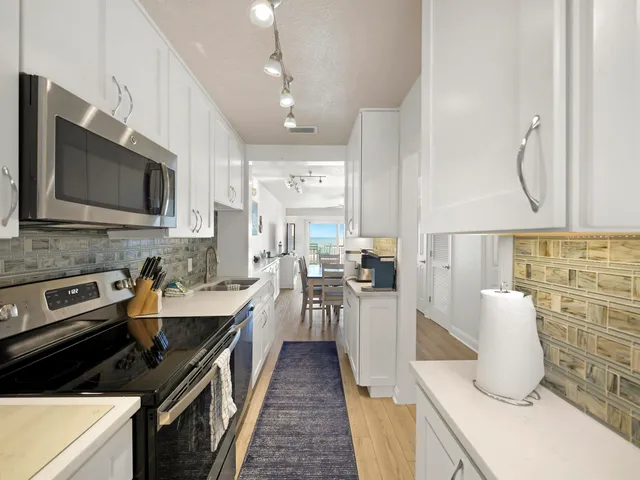 a kitchen with granite countertop a sink a stove top oven and cabinets