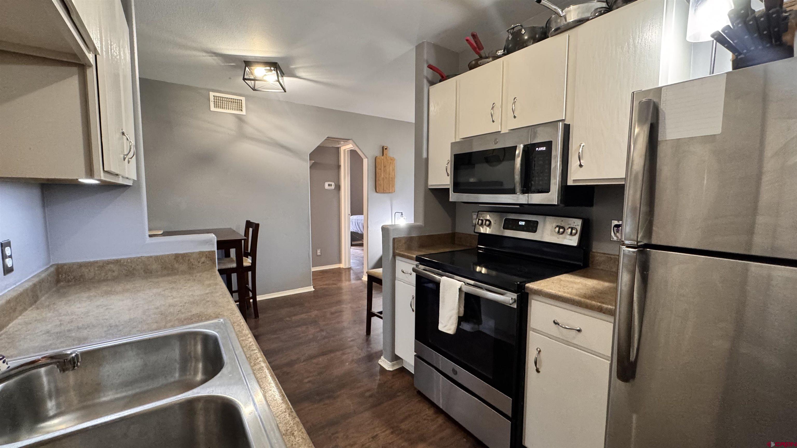 1100 Goeglein Gulch Road, Unit 204 Durango, CO 81301 - Photo 10 of 42 a kitchen with stainless steel appliances granite countertop a refrigerator a stove and a sink with wooden floor