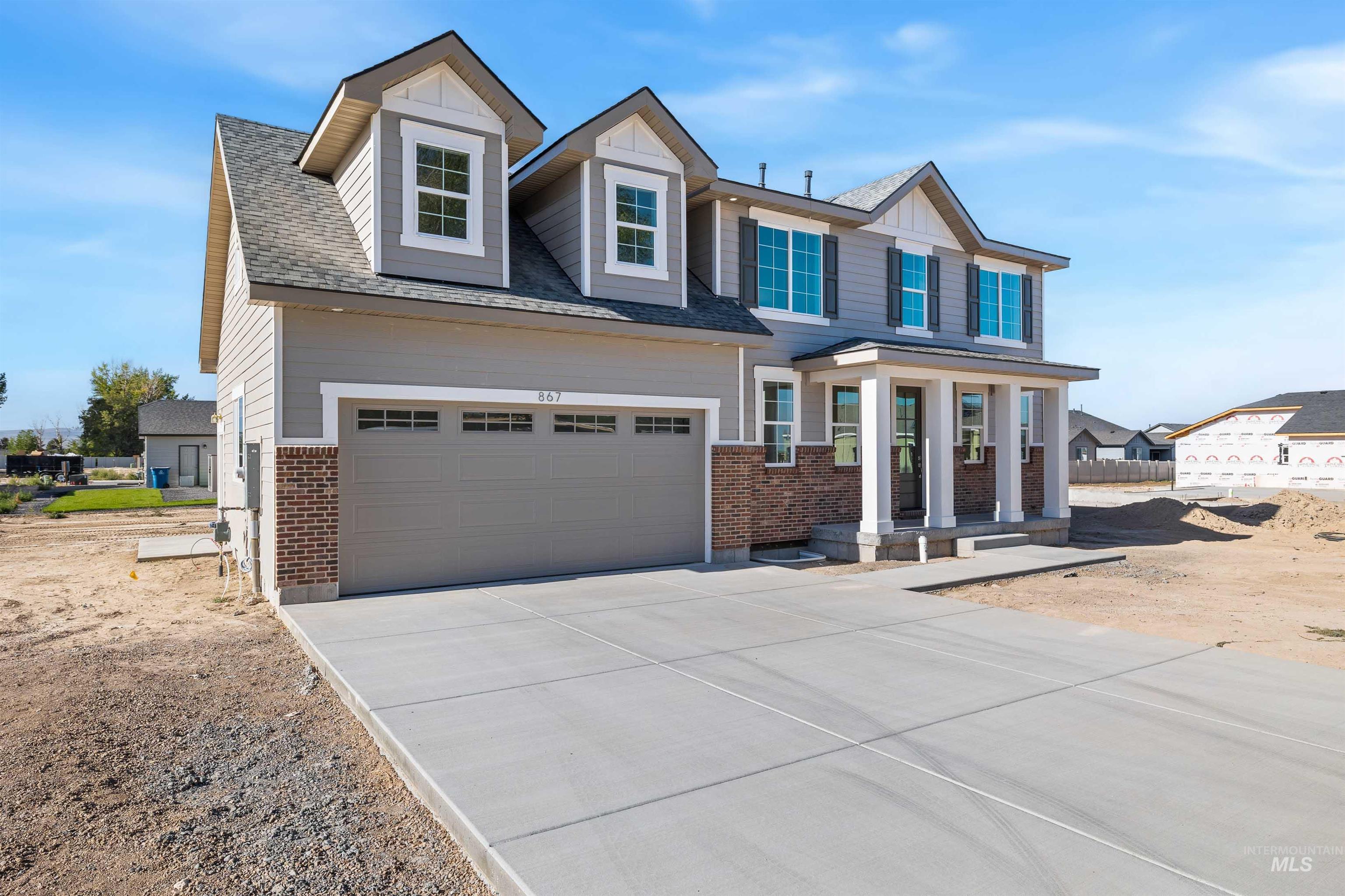 867 Adamite Road Kimberly, ID 83341 - Photo 24 of 24 View of front of home featuring brick siding, concrete driveway, roof with shingles, and covered porch