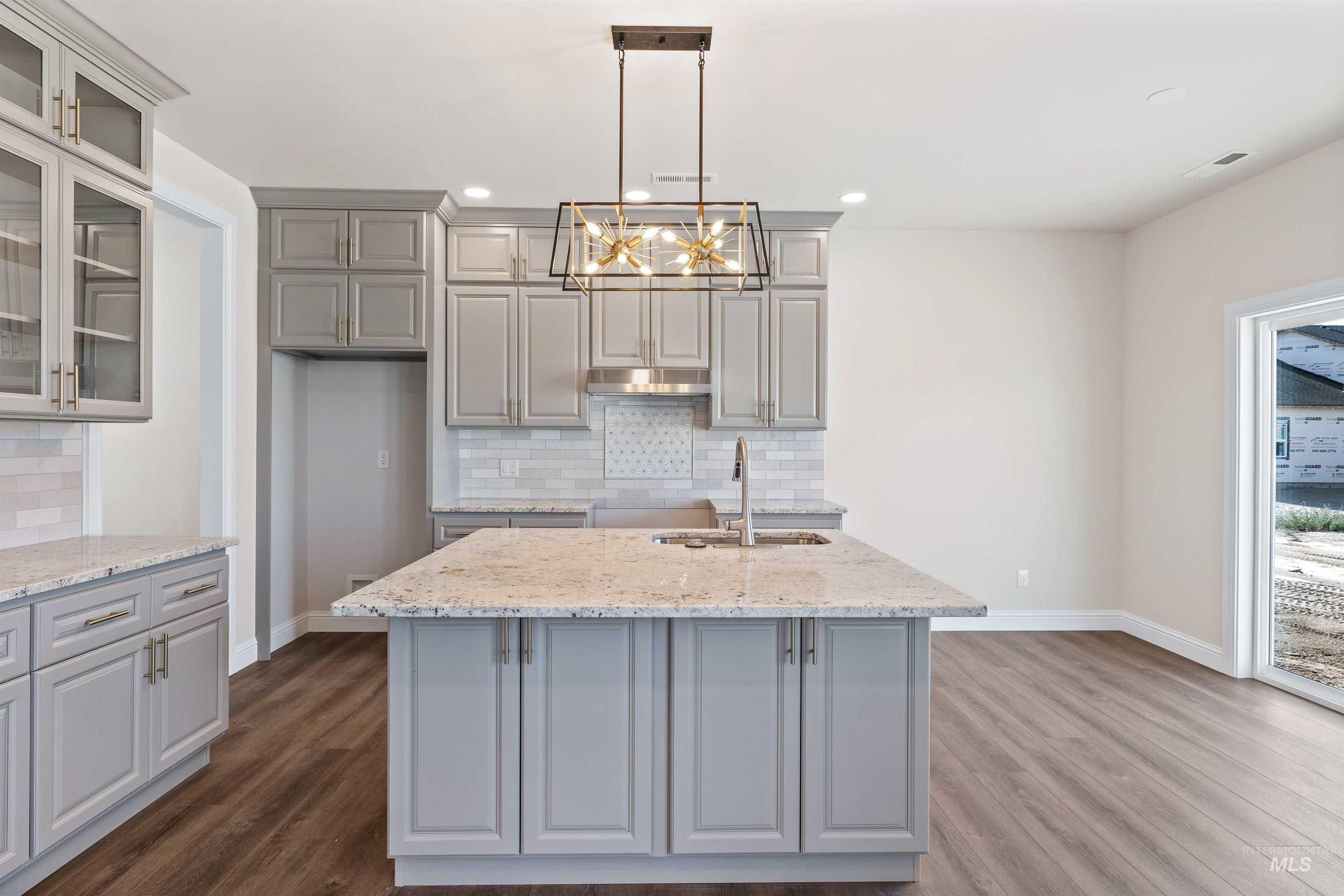 867 Adamite Road Kimberly, ID 83341 - Photo 6 of 24 Kitchen with gray cabinets, a chandelier, a center island with sink, dark wood-style floors, and light stone countertops