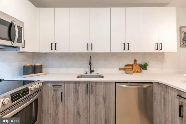 a kitchen with stainless steel appliances a sink a stove and white cabinets