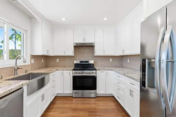 a view of an empty room with wooden floor and a ceiling fan