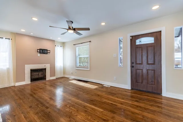 an empty room with windows fireplace and a kitchen view