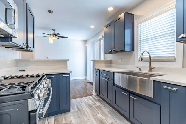 a kitchen with kitchen island granite countertop a sink cabinets and stainless steel appliances