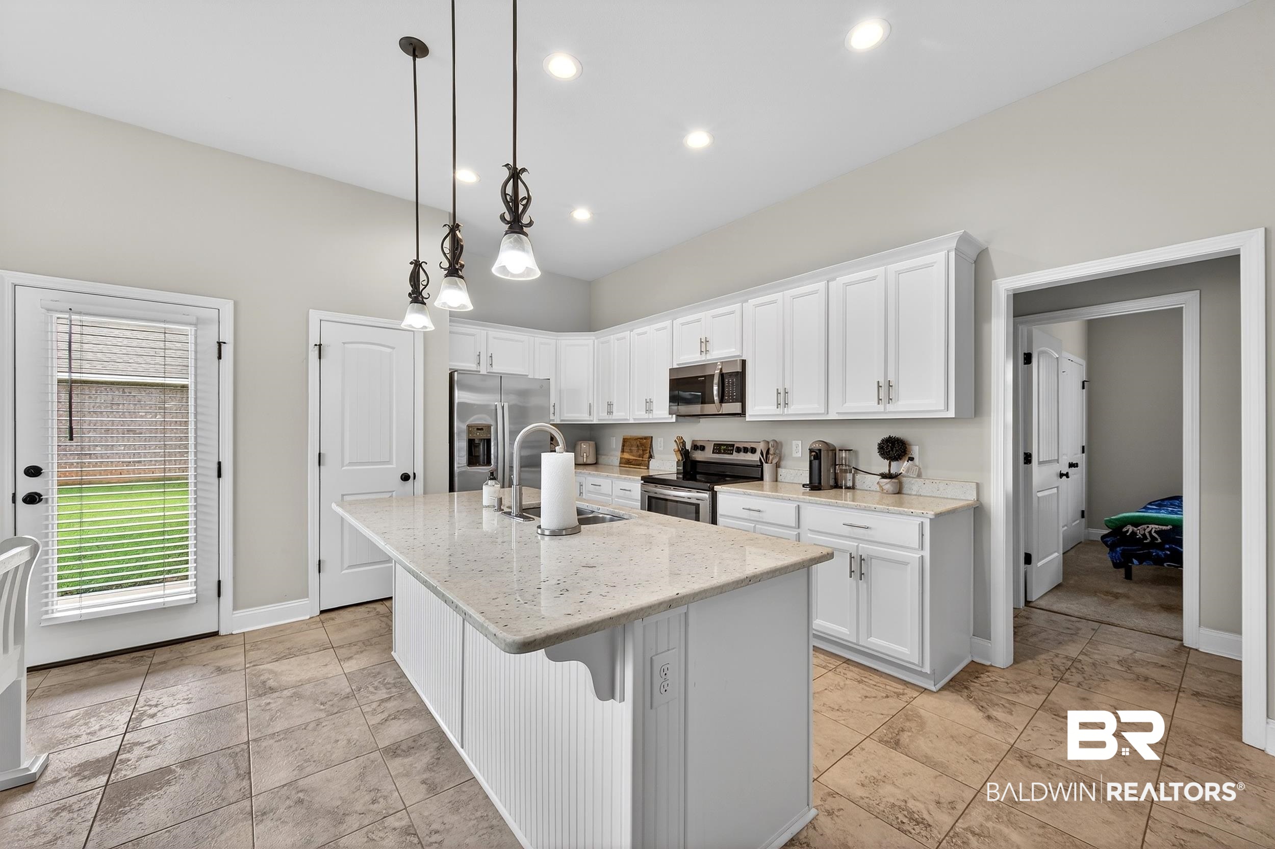 1084 Stella Road Foley, AL 36535 - Photo 15 of 31 Kitchen featuring white cabinetry, light stone countertops, an island with sink, a kitchen bar, and stainless steel appliances