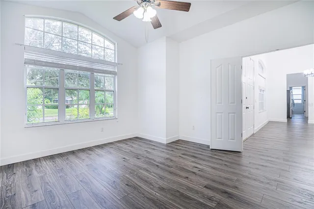 a view of an empty room with wooden floor and a window