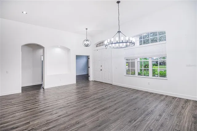 a view of a room with wooden floor chandelier and windows