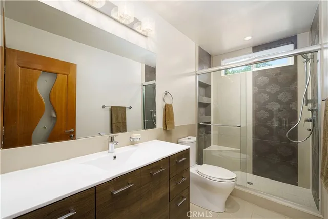 a bathroom with a granite countertop sink a toilet a mirror and shower